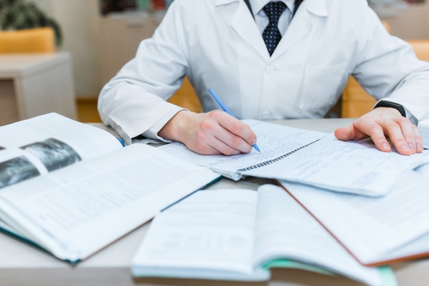 Ein medizinstudent für lehrbücher. das studium der chirurgie von einem mann mit krawatte in der bibliothek. krankenschwester. platz kopieren