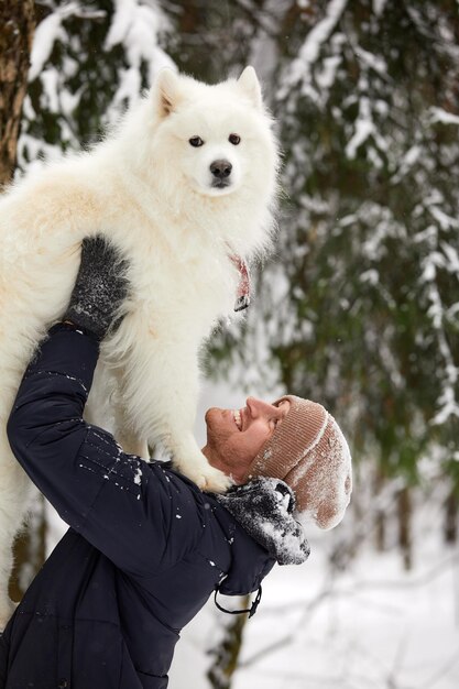 Ein Mensch und ein Hund sind beste Freunde Mensch und Hund gehen im Winter im tiefen Schnee an einem sonnigen Tag im verschneiten Wald spazieren