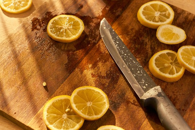 Ein Messer mit Zitronen darauf sitzt auf einem Schneidebrett mit einem Messer daneben.