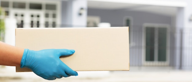 Ein Mitarbeiter, der eine Kiste in der Hand hält, liefert Produkte an Kunden nach Hause.