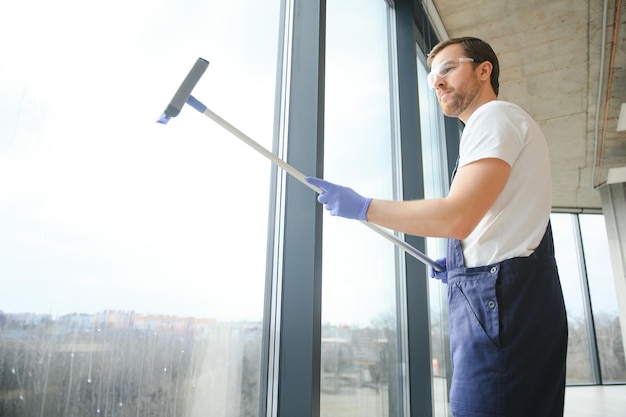 Ein Mitarbeiter eines professionellen Reinigungsdienstes wäscht das Glas der Fenster des Gebäudes Vitrinenreinigung für Geschäfte und Unternehmen