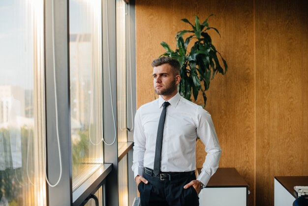 Ein Mitarbeiter im Büro steht am Fenster. Finanzen