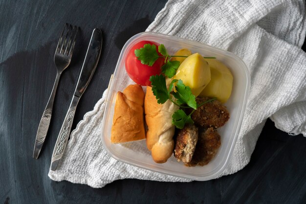 Ein mittagszeitkonzept, auf den tischen essend vom plastikbehälter mit fleisch und kartoffeln