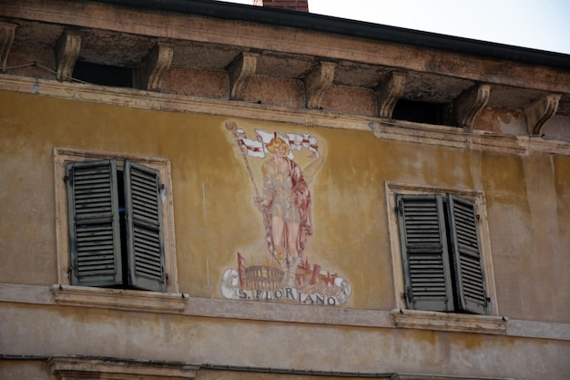 Ein mittelalterlicher christlicher Heiliger ist auf einem alten Haus zwischen zwei Fensterläden gemalt