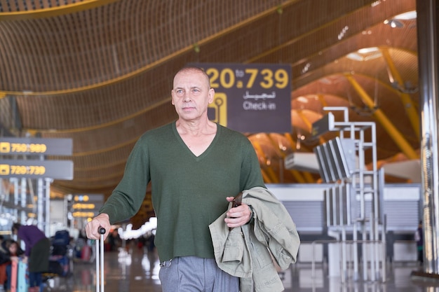 ein mittelalterlicher Mann geht mit einer Reisetasche durch den Flughafen