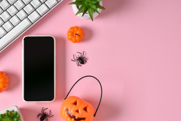 Ein Mockup mit Smartphones und Zubehör für den Halloween-Urlaub auf rosa Hintergrund Online-Glückwunsch