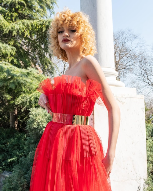 Ein Model in einem roten Kleid mit goldenem Gürtel