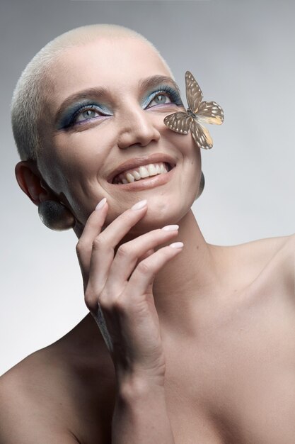 Ein Model mit strahlendem Make-up lächelt mit einem Schmetterling im Gesicht