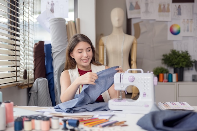 Ein Model wird von einem Modedesigner verwendet, um neue Designerkleidungsstücke anzuprobieren. Bei der Arbeit entwirft eine Unternehmerin in ihrem Stoffgeschäft neue Kleidung für einen Modedesigner.