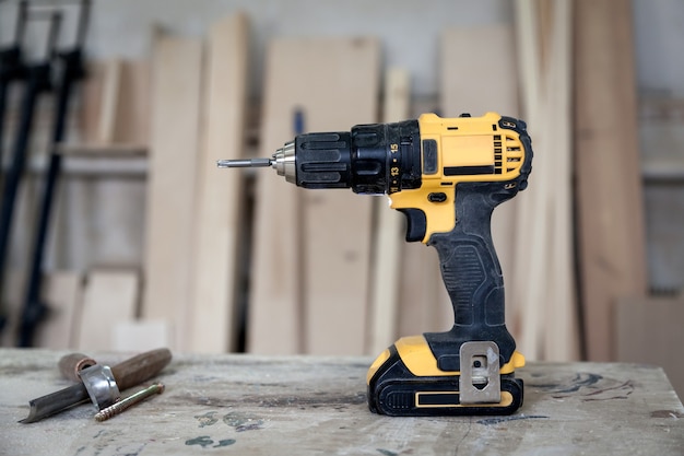 Ein moderner schwarz-gelber Schraubendreher auf einem Holztisch, Werkzeuge in der Werkstatt