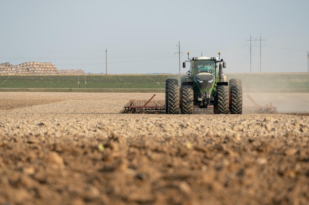 Ein moderner Traktor mit gezogenem Pflug arbeitet auf dem Feld Pflügen des Landes vor der Aussaat von Getreide Junglandwirt Traktorfahrer der landwirtschaftlichen Produktion