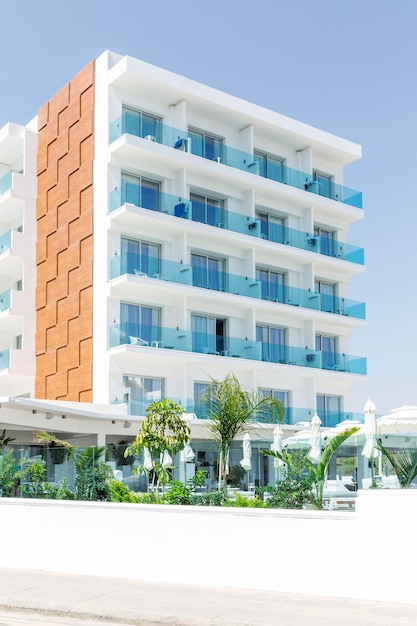 Ein modernes Gebäude eines kleinen Hotels mit einem Swimmingpool gegen einen blauen Himmel vertikal