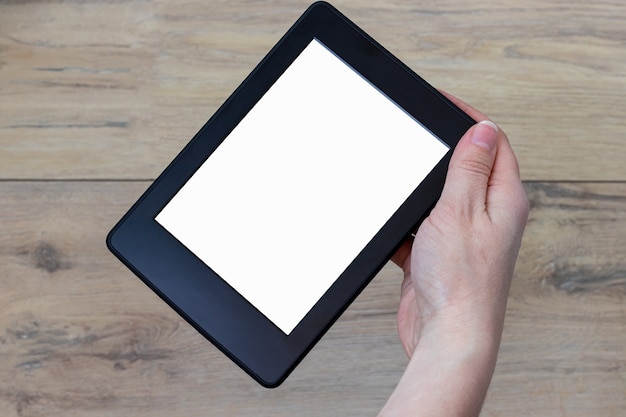 Ein modernes schwarzes elektronisches Buch mit einem weißen leeren leeren Bildschirm drehte sich in weiblicher Hand um 45 Grad