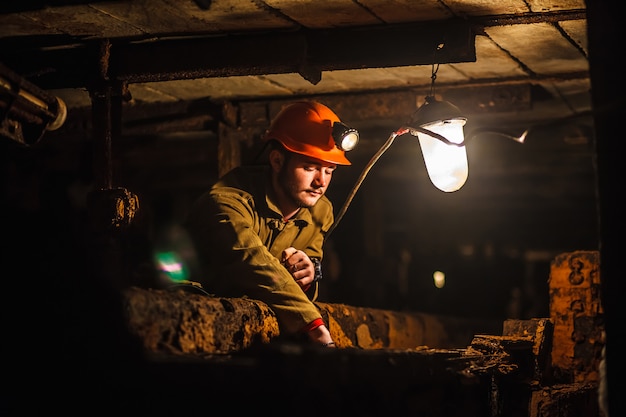 Ein müder Bergmann in einer Kohlengrube schaut ins Licht. Arbeit in einer Kohlenmine.