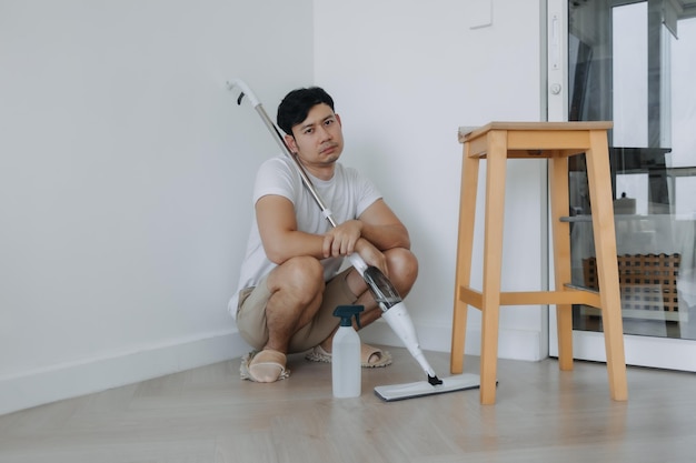 Foto ein müder hausbesitzer sitzt auf dem boden, nachdem er das zimmer abgewischt hat