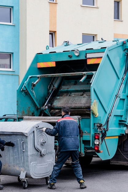 Ein Müllwagen holt Müll in einem Wohngebiet ab. Arbeiter laden einen Container mit Müll. Getrennte Sammlung und Entsorgung von Müll.