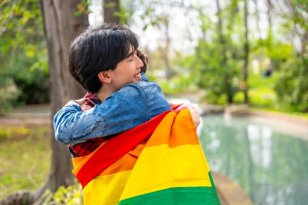 Ein multirassisches schwules Paar umarmt sich in einer LGBT-Flagge