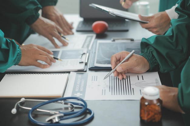 Ein multirassisches Team von Ärzten diskutiert einen Patienten, der im Foyer zusammengestellt ist und einen Tablet-Computer aus der Nähe betrachtet.