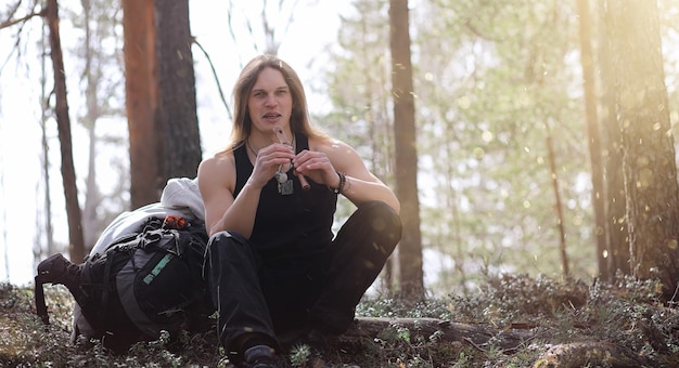 Ein Musiker mit einem Werkzeug in der Natur. Der Mensch spielt eine Flöte in einem Kiefernwald. Die Musik der Druiden im Frühlingswald.