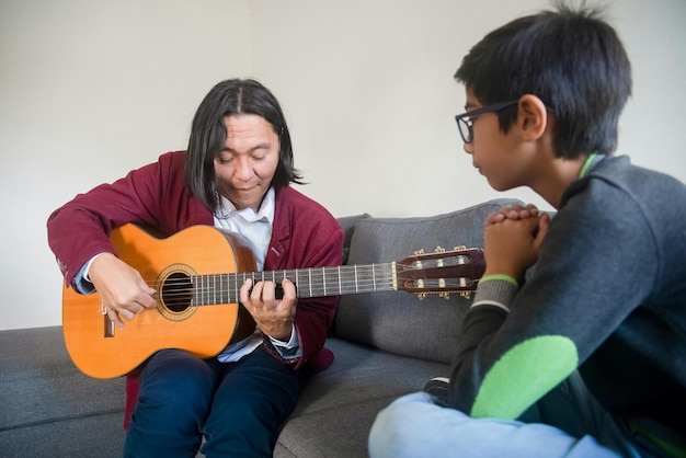Ein Musiklehrer zeigt einem Jungen, wie man Gitarre spielt