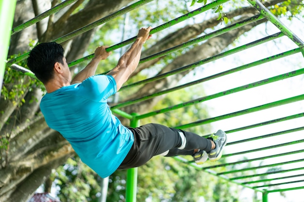 Ein muskulöser Mann in Sportkleidung, der Handübungen macht, perfektes Klimmzug zum Klettern im Park