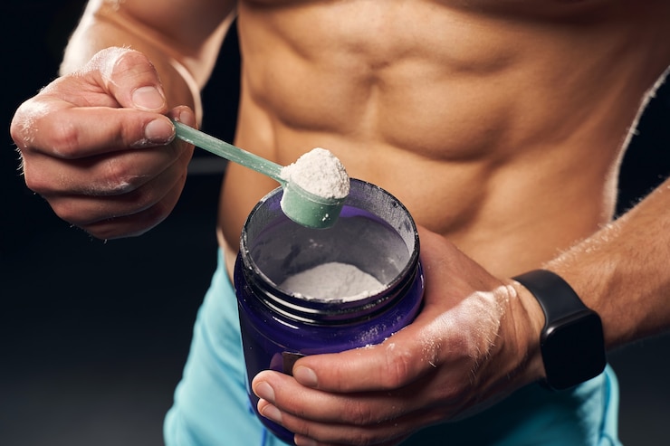 Foto ein muskulöser mann ohne hemd, der sportshorts trägt und proteinpulver aus einem glas schöpft