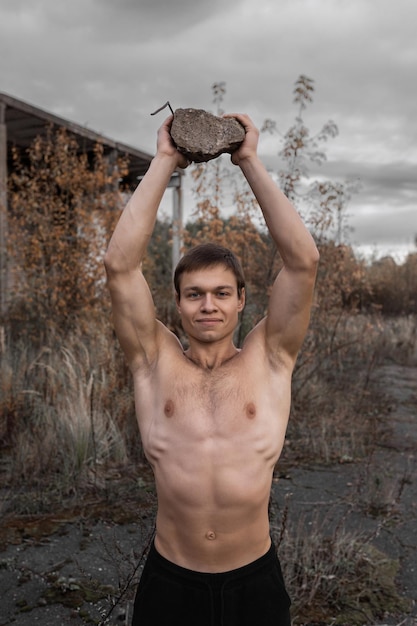 Ein muskulöser Typ trainiert im Frischluft-Workout und Crossfit vor dem Hintergrund einer alten Fabrik