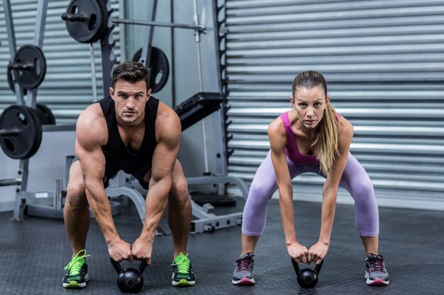 Ein muskulöses Paar, das kettlebells anhebt