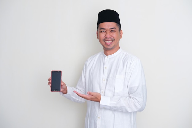 Ein muslimischer asiatischer Mann lächelt und zeigt einen leeren Handybildschirm