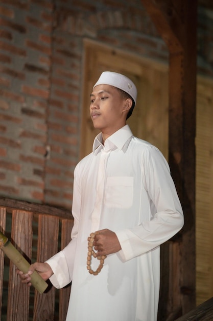 Ein muslimischer Mann, der auf der Treppe vor dem traditionellen Haus steht