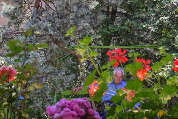 Foto ein nachdenklicher älterer mann sitzt auf einer bank inmitten von pflanzen und bäumen im park
