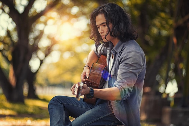 Foto ein nachdenklicher junger mann spielt gitarre
