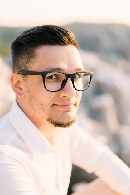 Foto ein nachdenklicher mann mit brille sitzt auf einem felsen im sonnenporträt