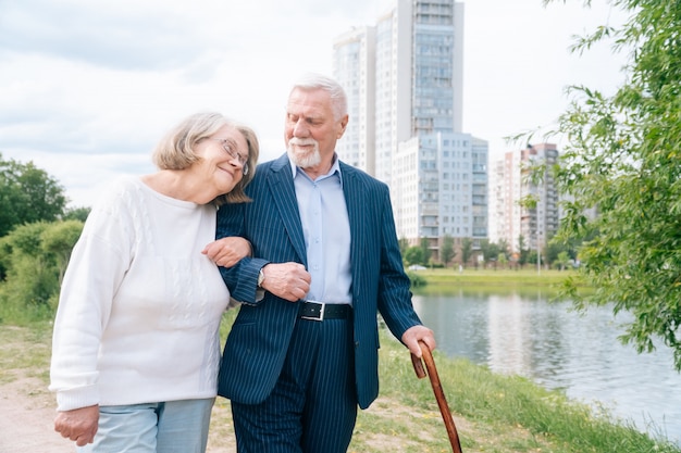 Ein nachdenkliches älteres Ehepaar mit einem stilvollen Stock geht im Park an der frischen Luft spazieren