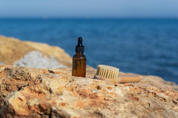 Ein natürliches ätherisches Öl oder Serum in einer braunen Tropfflasche, die auf den Steinen am Meer steht