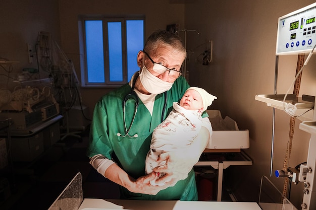 Ein Neonatologe hält ein Neugeborenes im Krankenhaus in den Armen