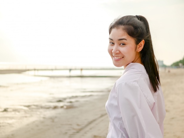 Ein nettes asiatisches Mädchen, in einem Reisemoment, sie stehend wirft auf und lächelt für machen ein Foto an im Freien.