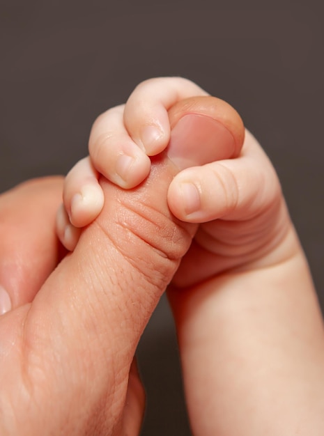 Ein neugeborenes Baby hält sich fest an der Fingernahaufnahme der Eltern Das Konzept der Elternschaft