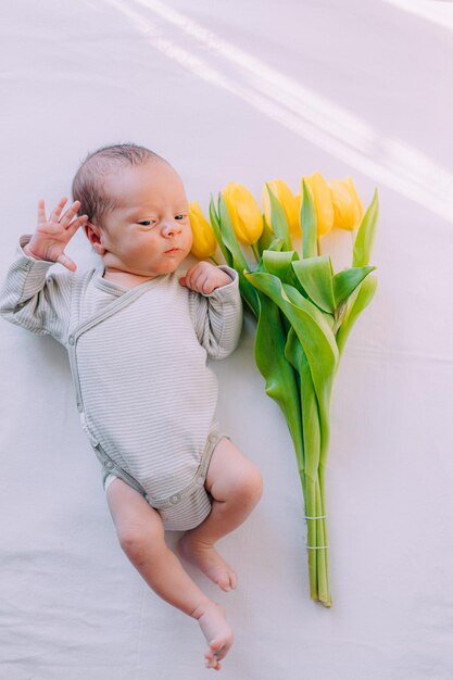 Ein neugeborenes Baby mit einem Strauß Tulpen 8. März Baby und Blumen Gelbe Tulpen