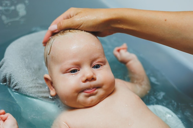 Ein Neugeborenes badet, die Eltern baden das Kind, das Neugeborene wird gebadet, das Neuborene lächelt, die Betreuung des Babys.