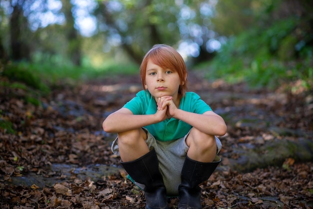 Ein neunjähriger Junge sitzt allein auf einem Weg im Wald