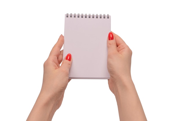 Ein Notizbuch mit leerem weißem Papier in Frauenhänden mit roten Nägeln