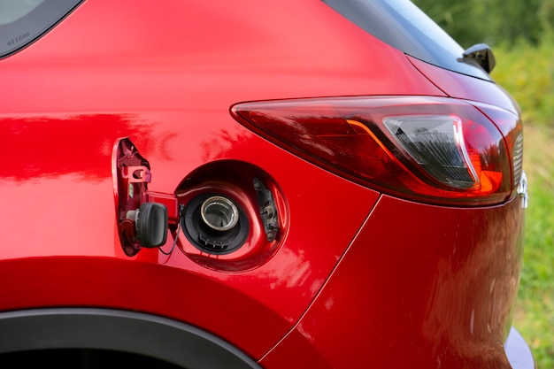 Ein offener Tankdeckel eines roten Autos zum Einfüllen von Benzin oder Dieselkraftstoff in den Gastank