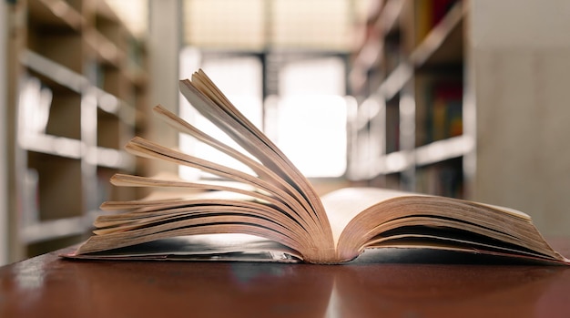 Ein offenes Buch oder Lehrbuch in der Bibliothek mit Licht aus dem Fenster auf dem Lesetisch