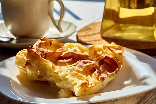 Ein Omelett in einem Teller auf einem Holztisch eine Teekanne und eine Tasse