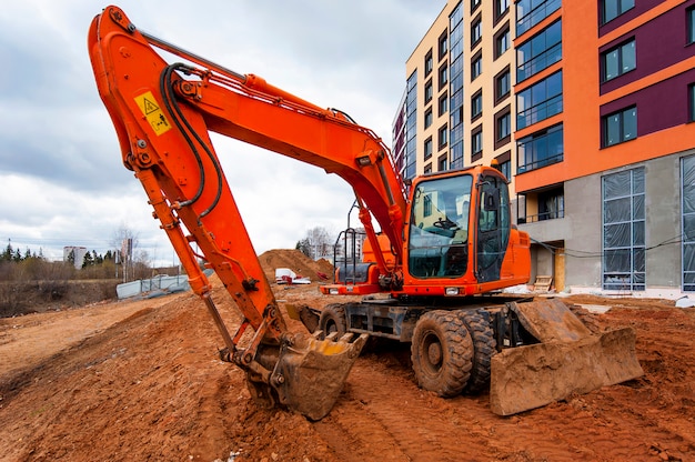 Foto ein orangefarbener bagger steht neben einem bunten haus