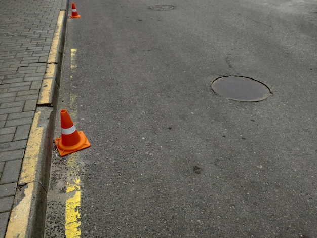 Ein orangefarbener Kegel am Straßenrand mit einer gelben Linie.