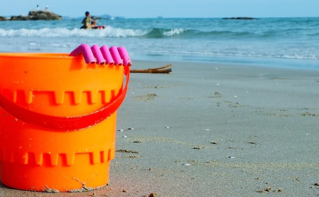 Ein orangefarbener Spielzeugbecken wird auf dem Strand platziert