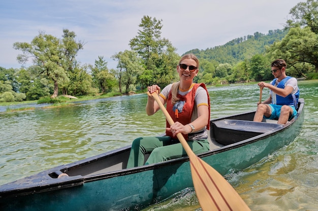 Ein paar abenteuerlustige Entdeckerfreunde fahren in einem wilden Fluss, umgeben von der wunderschönen Natur, Kanu