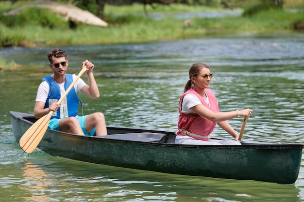 Ein paar abenteuerlustige Entdeckerfreunde fahren in einem wilden Fluss, umgeben von der wunderschönen Natur, Kanu